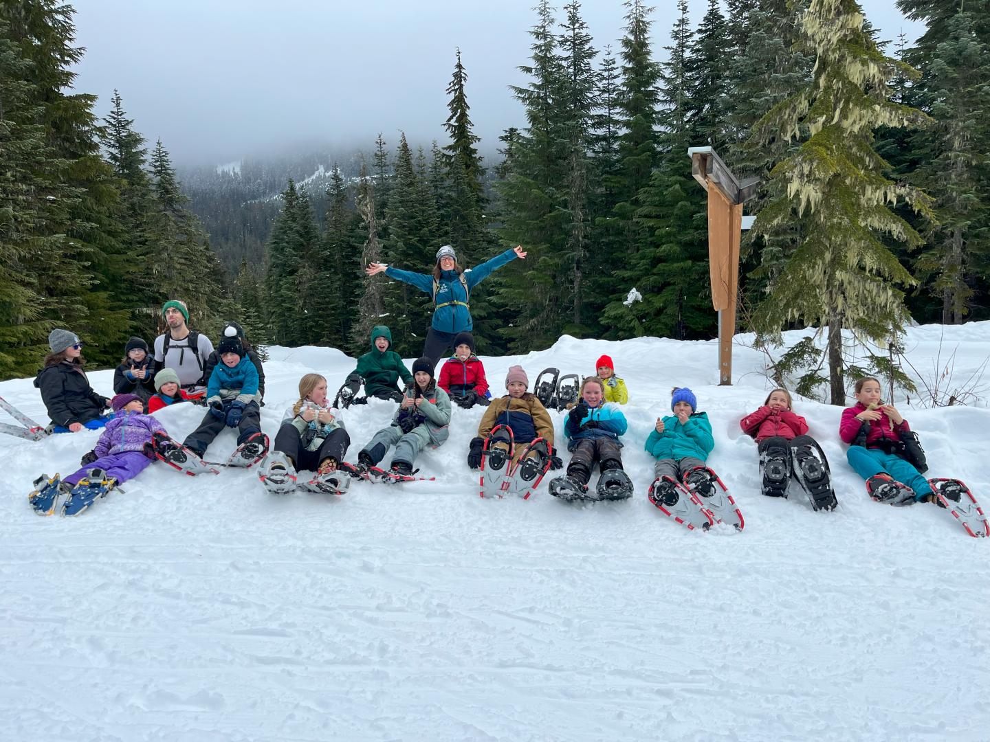 Group of children laying in the snow wearing snowshoes