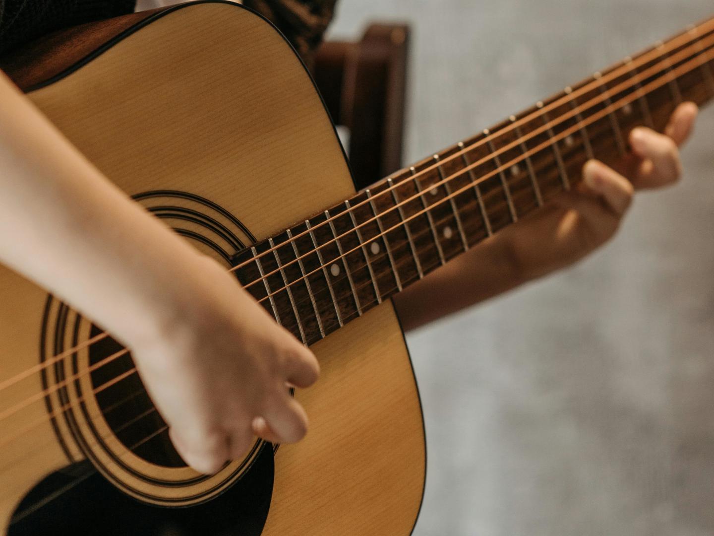 Hands playing an acoustic guitar.
