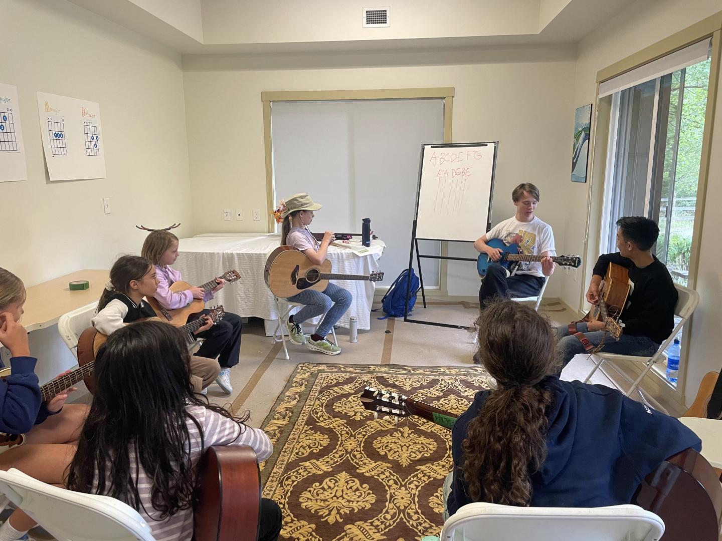 Children in a classroom sitting in a circle playing guitars.