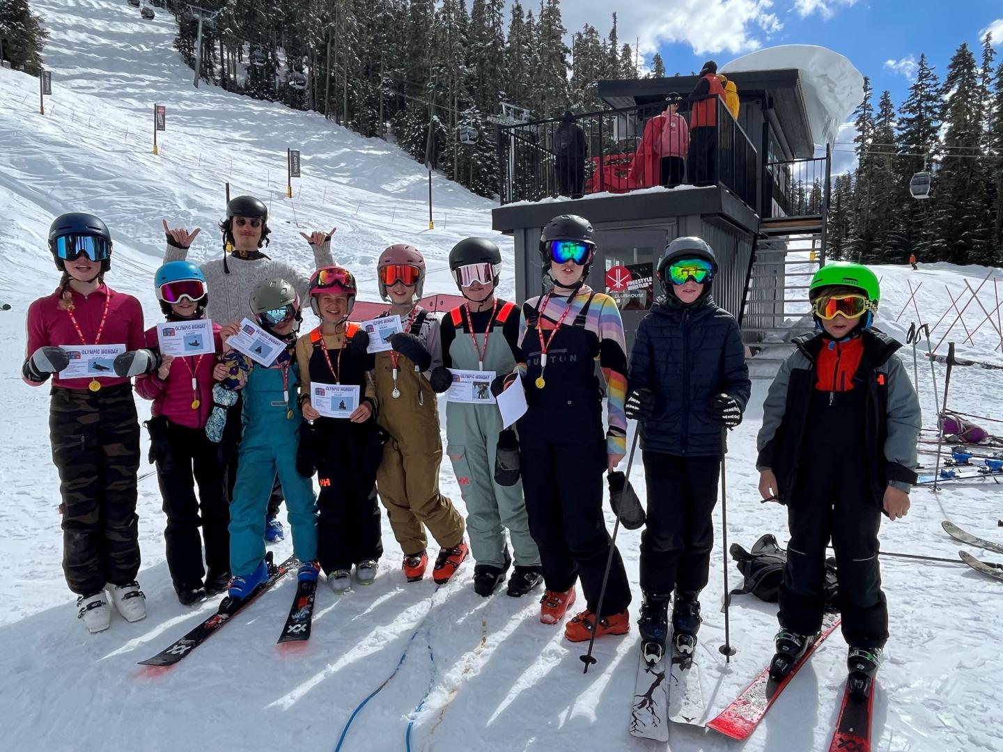 Group of skiers posing on a snowy slope beneath evergreen trees.